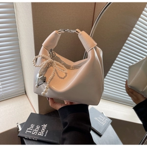 Détail du sac hobo blanc avec nœud en perles, pendentif cœur et texture en cuir brillant