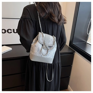 Vista posteriore di una modella con borsa a secchiello damascata e catena d'argento