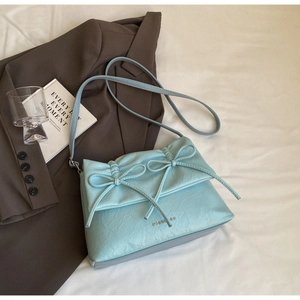 Close-up of mint blue crossbody bag with ribbon bows and pleated texture detail