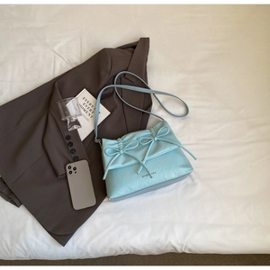 Detail of light blue pleated faux leather bag featuring elegant twin bow decorations