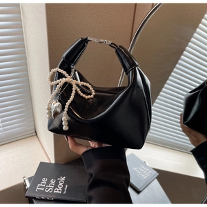 Détail du sac hobo en cuir verni noir avec nœud en perles et pendentif cœur argenté