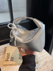 Sac à main argenté métallisé avec nœud en perles et pendentif cœur au design moderne