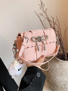 Pink woven crossbody bag with rhinestone bow and sheep charm held by a person