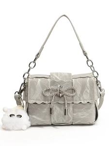 Silver pleated shoulder bag with diamond bow and cute plush pendant on white background