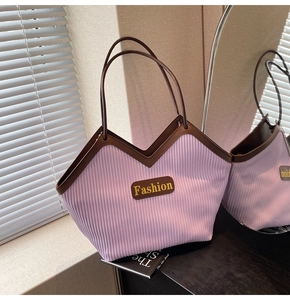 Detail of lavender pleated tote bag with brown leather handles and Fashion emblem
