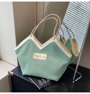 Detail of light green pleated tote bag with cream leather trim and Fashion logo badge