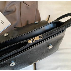 Macro detail of glossy pleated black leather surface with zipper and silver hardware