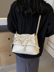Chic beige ballet-style crossbody bag with pleated texture and stylish bow accents