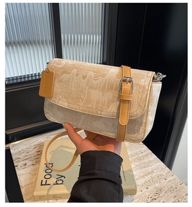 Detail of beige wavy print crossbody bag with leather trim and metallic buckle