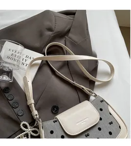 Close-up of small square bag featuring gray polka dot fabric and pearl bow charm detail