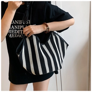 Black and white striped tote bag showing real-life size and draped shape on shoulder