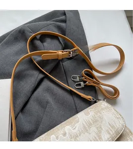 Detail of adjustable tan leather shoulder strap with silver buckle on a stylish crossbody bag
