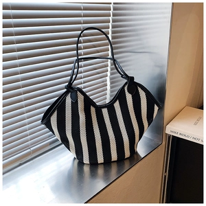 Close-up of black and white striped mesh tote bag featuring premium leather trim details