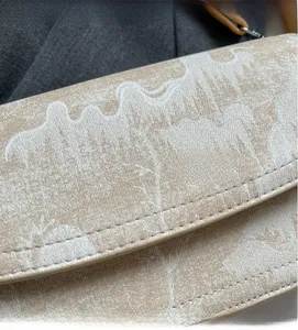 Close-up of beige printed handbag showing textured fabric and delicate stitching detail
