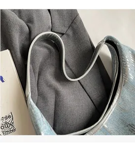 Detail shot of sturdy leather handles on sequined denim tote bag with reinforced stitching