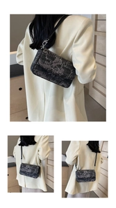 Detail of dark woven crossbody bag with abstract texture and leather strap on model