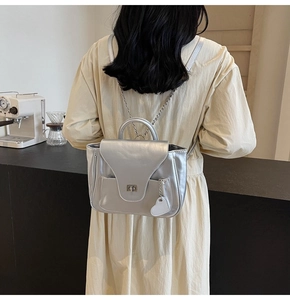 Mini sac à dos argenté avec chaîne et pendentif cœur porté par un mannequin