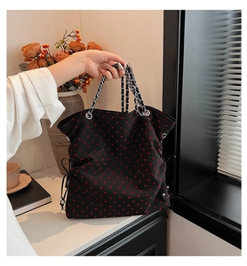 Detail of black heart print tote bag with silver chain handle and drawstring side decor