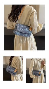 Detail of blue mountain landscape print denim crossbody bag with leather strap and metal buckle