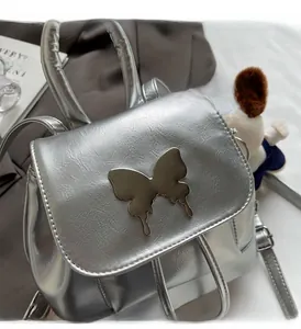 Détail du mini sac à dos argenté avec boucle papillon et texture cuir froissé
