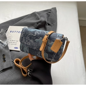 Detail of blue denim landscape print crossbody bag with tan leather shoulder strap