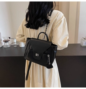 Détail d'un sac à dos en cuir noir avec fermoir tournant et chaîne à breloque coeur