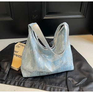 Close-up of light blue sequined tote bag with silver wavy texture on black leather background