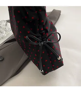 Detail of black heart print tote bag featuring a leather bow with silver bead accents