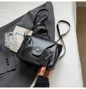 Détail d'un sac à main en cuir noir brillant avec pendentif cœur et fermoir métallique