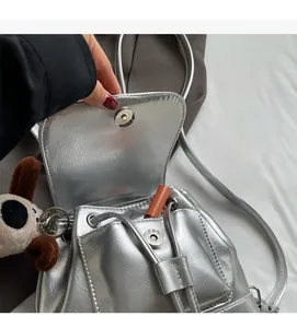 Détail du sac à dos argenté métallisé avec rabat magnétique et pendentif petit chien
