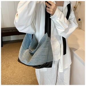 Detail of spacious denim tote bag featuring black leather trim and handles for daily use