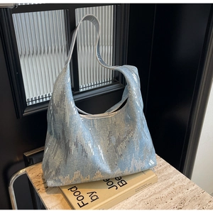 Detail of blue denim hobo bag with silver sequins on marble surface with props