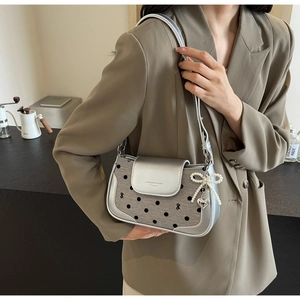 Detail of silver gray shoulder bag with polka dot pattern and pearl butterfly charm