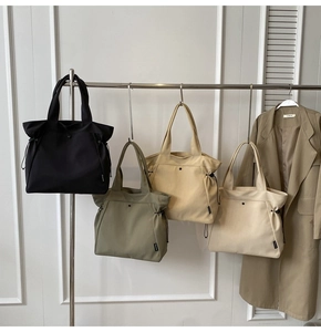 Detailed view of large canvas tote bags in four neutral colors with drawstring side design