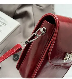 Detailed close-up of glossy dark red patent leather bag with silver bee metal hardware