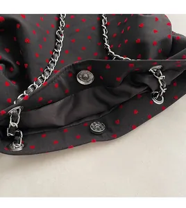 Detail of silver magnetic buckle and red heart print on black fabric tote bag