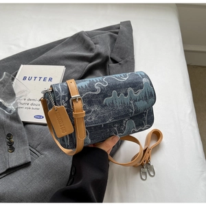 Detail of blue jacquard crossbody bag with landscape pattern and khaki leather trim