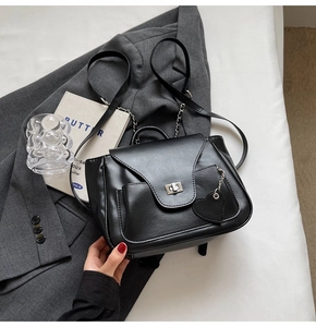 Détail du sac en cuir noir avec fermoir rotatif argenté et charm en forme de cœur