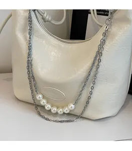 Dettaglio della borsa hobo in pelle bianca a pieghe con catena e perle ornamentali