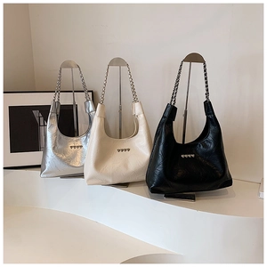 Detailed close-up of three shoulder bags in silver, white, and black with heart hardware