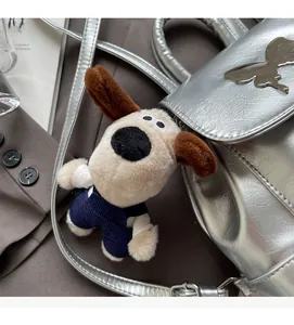 Charmant pendentif chien Gromit en peluche avec salopette bleue sur un sac argenté