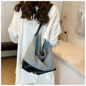 Rear view of model wearing a large light blue denim hobo bag with black contrast strap