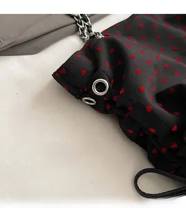Close-up of black tote with red heart prints and silver chain strap details