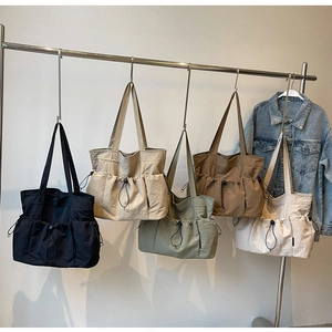 Five colors of large nylon tote bags with drawstring pockets hanging on a metal rack
