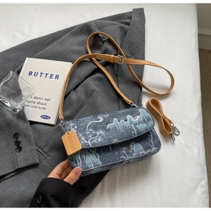 Detail of blue denim shoulder bag with white landscape jacquard and leather tag