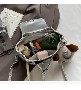 Détail de l'intérieur d'un mini sac à dos argenté avec smartphone et cosmétiques