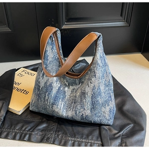 Close-up of blue denim canvas tote with silver sequins and brown leather straps