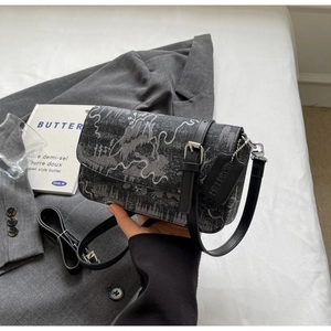 Close-up of ink-print crossbody bag with leather buckle and dual shoulder straps