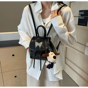 Détail du mini sac à dos noir brillant avec papillon argenté et breloque en peluche