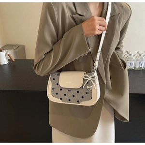 Detail of beige shoulder bag with polka dot canvas and pearl bow charm accessory